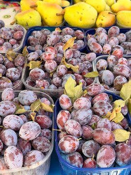 Fresh ripe plums for sale at farmers market, juicy purple fruit displayed on wooden counter
