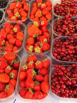 Assorted fresh berries in plastic containers at farmers market - raspberries, blackcurrants and blueberries for sale