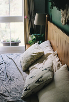 A cozy bed with patterned pillows next to a bright window.