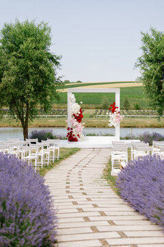 Purple flowers and chairs between path and decorated stage with roses