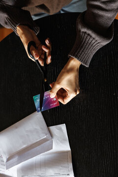Cropped woman cutting credit card at desk with financial documents