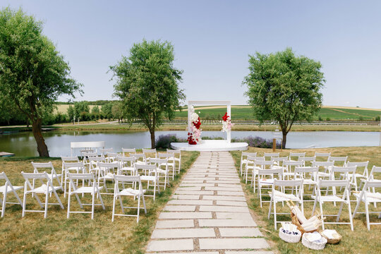 Chairs between path and decorated stage with roses on lake shore