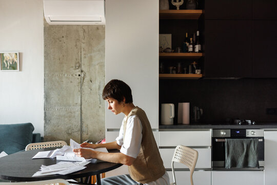 Side view of young thoughtful woman checking financial documents