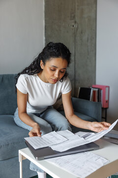 Young focused beautiful black woman checking financial documents
