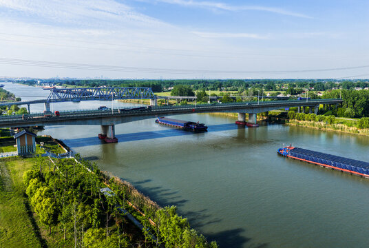 highway bridge over river with cargo barges passing below