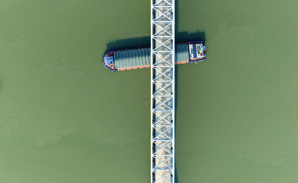 highway bridge over river with cargo barges passing below