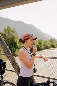 Woman eating snack on bridge during summer cycling trip