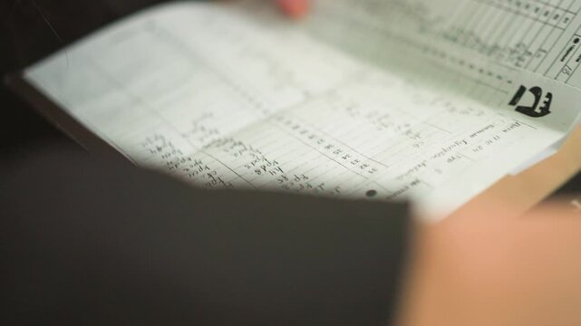 Close up of person hands turning pages of open notebook with handwritten notes and numerical data. scene focuses on detailed writing including numbers in columns and text entries suggesting