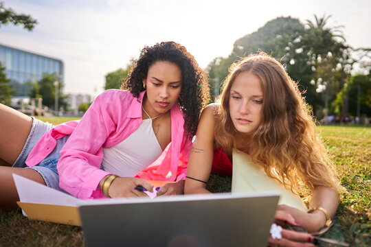 Diverse students studying together outdoors with laptop