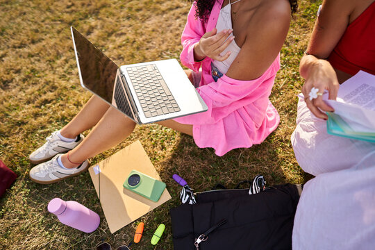 Students learning outdoors using laptop on grass
