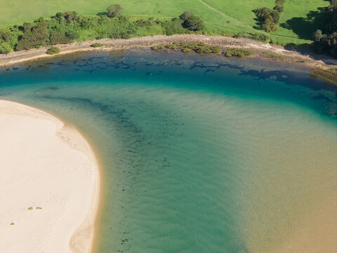 A channel in a coastal river rounding a sandy beach