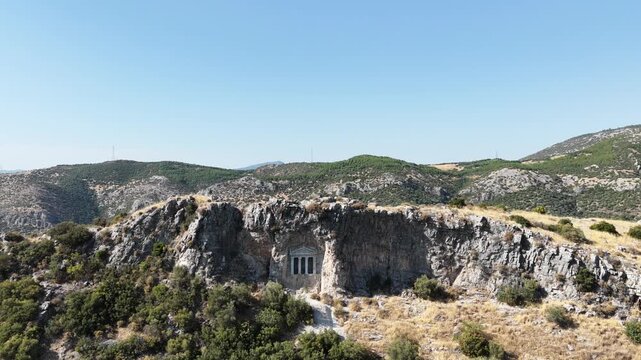 4K aerial video of the Nişanyan Rock Tomb in Şirince, Turkey, showcasing the ancient rock-cut burial site and its surrounding natural landscape.