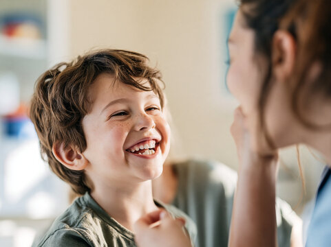 Happy child boy smiling brown hair casual clothing indoor sunlight joyful communication therapy session speech therapy stuttering fluency disorder learning interaction positive emotion childhood