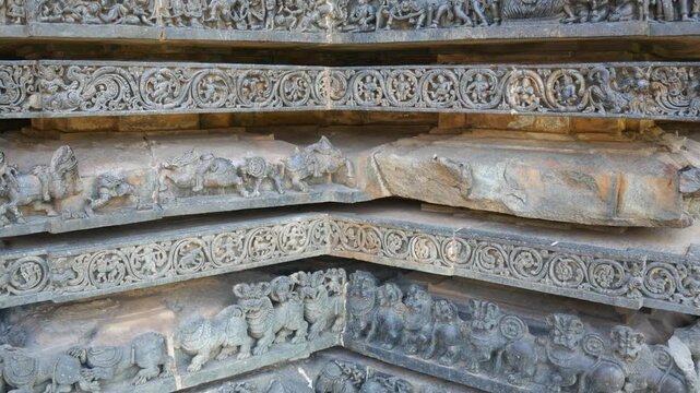 PAN: Intricately carved stone relief at the historic Hoysaleswara Temple in Halebidu, Karnataka, India, depicting richly ornamented Hindu deities and figures in detailed Hoysala architecture