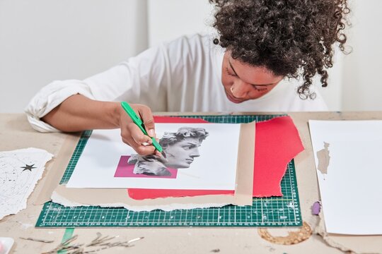 Black woman designer using a scalpel to cut a paper collage, focused on tactile textures and torn edges for zine and album artwork design