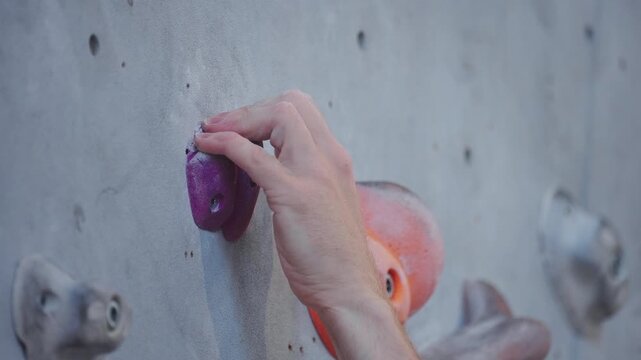 Close Up of Climber Hand Gripping Small Hold on Indoor Climbing Wall
