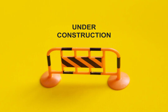 Under construction sign on yellow background for roadwork, building renovation, safety, and restricted access