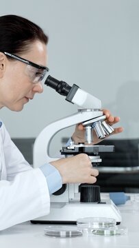 Female scientist looking into a microscope. Working in a medical research laboratory and conducting experiments for scientific innovation. Analyzing biological samples