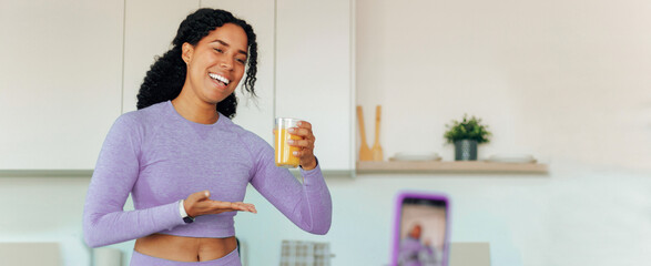 Smiling Black Female Fitness Enthusiast Holding Refreshing Smoothie While Engaging With Camera In...