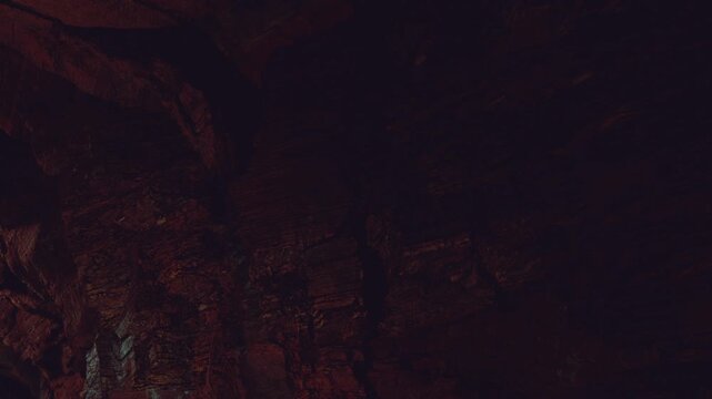 A cave scene shows the rough texture of a wall illuminated by light. The dark surroundings contrast with the brighter area. The setting is mysterious and natural.