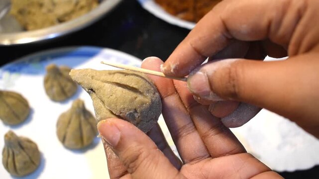 Hand designing modak with a toothpick, showcasing a handmade Indian kitchen technique for Ganesh Chaturthi.