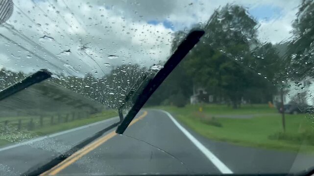 Driving on a rural road in the rain with windshield wipers on