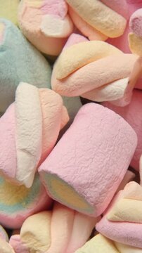 Colorful pastel marshmallows rotating close up. Vertical background video of sweet marshmallow texture. Spinning soft fluffy candy pile backdrop for childhood memories and sugar food concept.