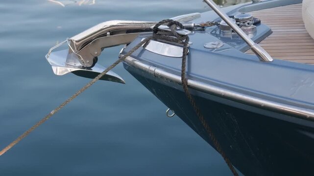 Close-up of a yacht's bow with a folded anchor, rope tied to a cleat and teak deck, Port Hercule, Monaco
