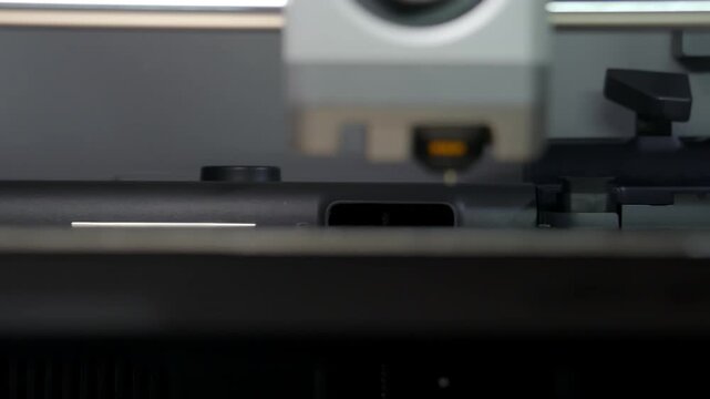 Industrial machine precisely positions tool above workpiece. Close-up highlights precision engineering and automation process. Dark background emphasizes machine's focused operation
