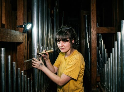 Pipe Organ Craftswoman Adjusting Metal Pipes in Workshop
