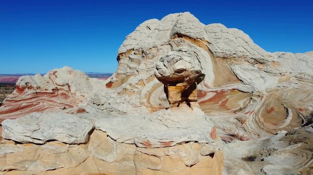 Hiker stands beneath swirling sandstone formations at White Pocket Arizona, Aerial desert footage reveals sculpted rock patterns and vivid natural colors