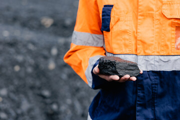 Obraz premium Worker holding coal sample in industrial outdoor setting