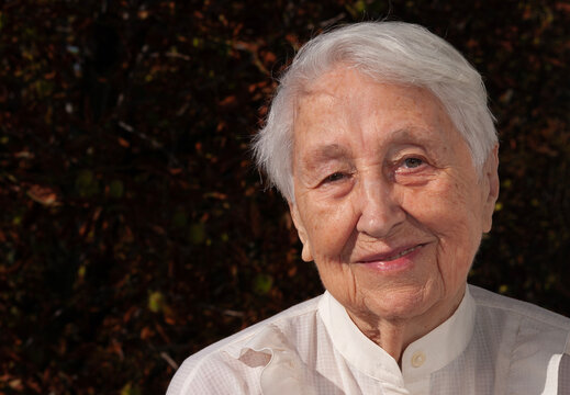 Positive senior woman smiling at home over trees on balcony