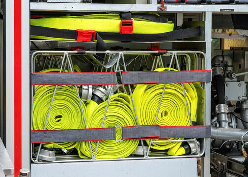Rolled yellow fire hoses organized inside a modern fire engine truck compartment. Specialized equipment ready for professional firefighting and rescue operations