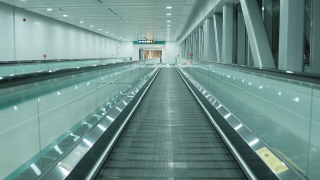 Moving walkway carries viewer through an empty modern airport terminal, passing glass railings and structural columns under ceiling lights