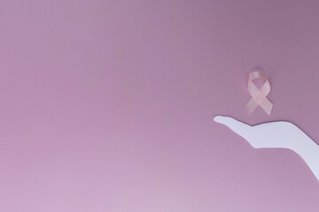 Hand cutout holding pink ribbon for breast cancer awareness