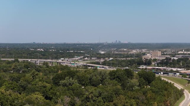Aerial of interstate 470 interchange and wooden urban areas in Kansas City Missouri showing major overpasses and distant city view
