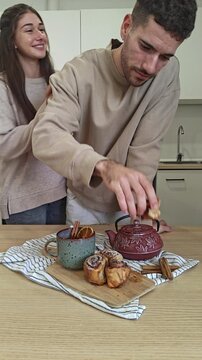 Woman stealing a cinnamon roll from her boyfriend at a cozy breakfast table, playful couple moment