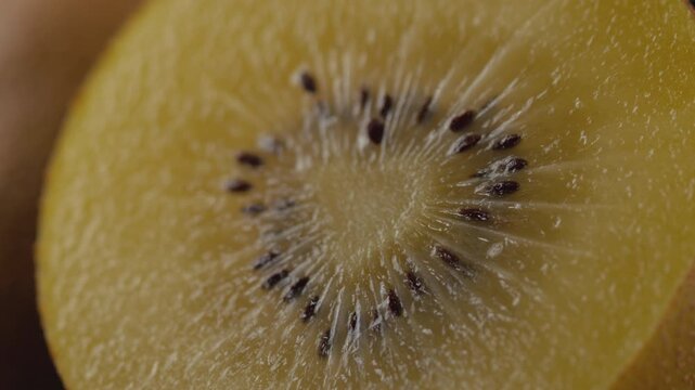 Extreme macro shot of ripe golden kiwi pulp and seeds filling the frame, showing rich juicy texture with slow rotation and artistic lighting. Perfect for healthy eating, gourmet food, culinary content