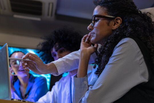 Candid moment as a diverse, multiethnic software team study a handheld device as a team in a modern technology office bathed in blue light, reflecting diversity and innovation (frame 520)
