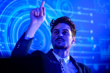 Businessman in dark suit and tie marks an insight in the air seated and raising a stylus before...
