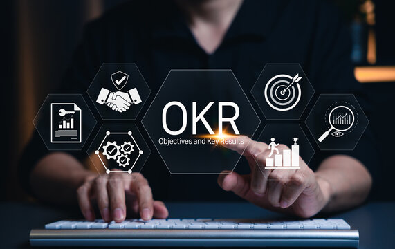 OKR Objectives and Key Results Business Strategy Concept. Businessman typing on keyboard with OKR icons, target, charts, gears, strategic planning, performance tracking, achieving corporate objective