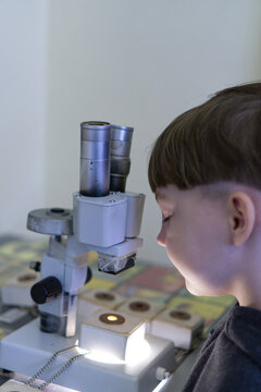 Curious boy looking through a microscope at a science exhibition or museum