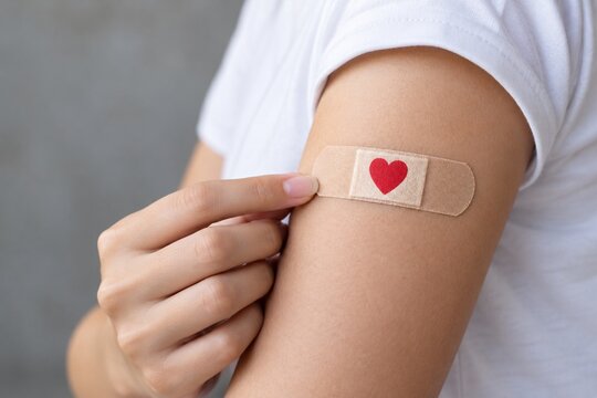Adhesive bandage with red heart on upper arm