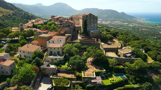 Pigna Corsica drone flight authentic hilltop village red tile roofs swimming pools, scenic Balagne coastline and Mediterranean sea panorama . Most beautiful villages France