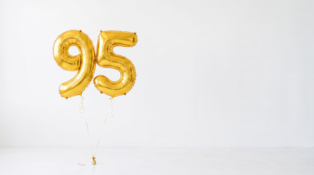 Gold number 95 foil balloons floating on a clean white background with copy space, festive decoration for 95th birthday, anniversary, jubilee and milestone celebration.