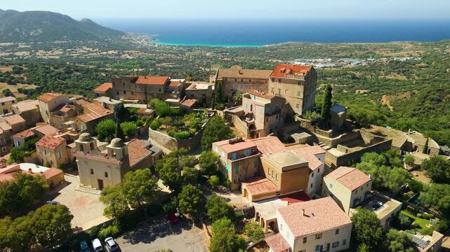 Pinia village Corsica drone aerial view traditional red roof houses hilltop coast sea panorama. Scenic Corsican mountain village overflight, Mediterranean island France travel 4K.