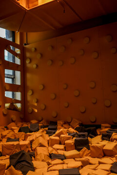 Indoor trampoline park with a large foam pit filled with colorful cubes and climbing wall
