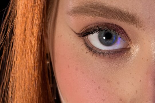 Close-up of an eye with eyeliner and red hair on a woman's face