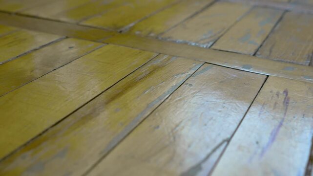 Old worn yellow wooden parquet floor with cracked and peeling varnish background
